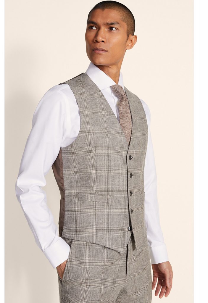 how to style a men's waistcoat; a man wearing a checked grey waistcoat looks to his left 