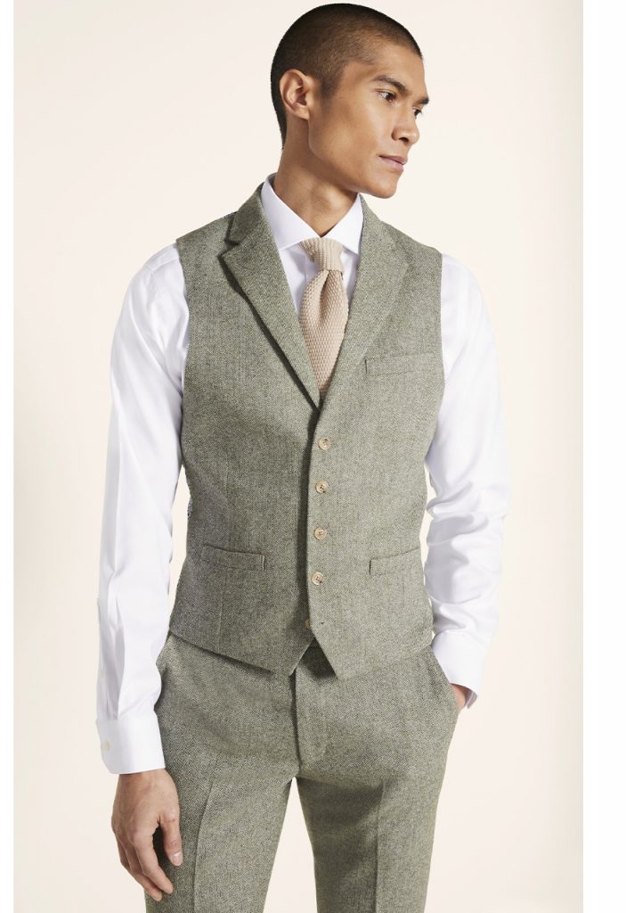 how to style a men's waistcoat; man wearing buttoned green waistcoat and a knitted tie 