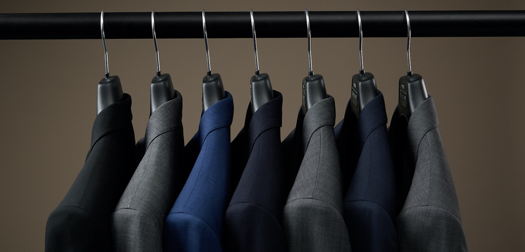 Perfectly cared for suits hung on a rack.