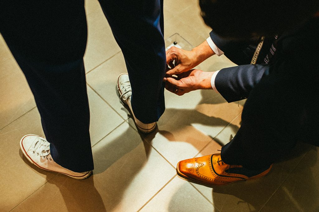 Man in white trainers having navy suit trousers fitted to buy 