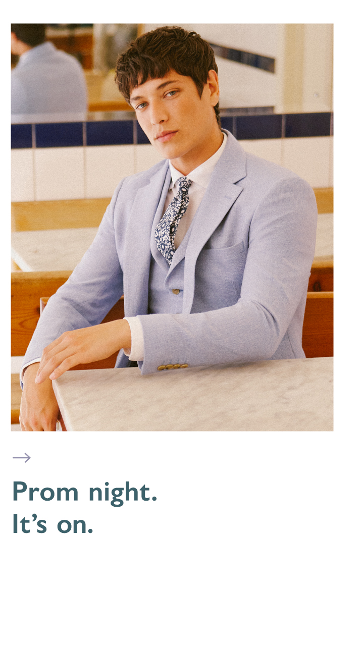 Man sat in sky light blue prom suit and floral tie.