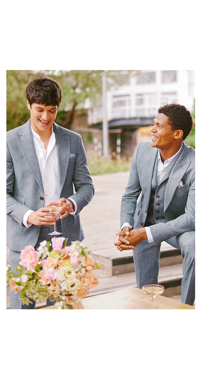 Two men laughing at a wedding in grey summer wedding suits 