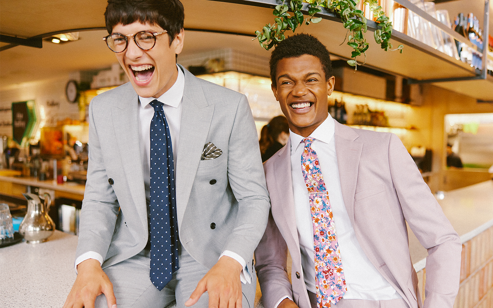 Men laughing at a wedding in grey summer suits and pocket squares and patterned ties 