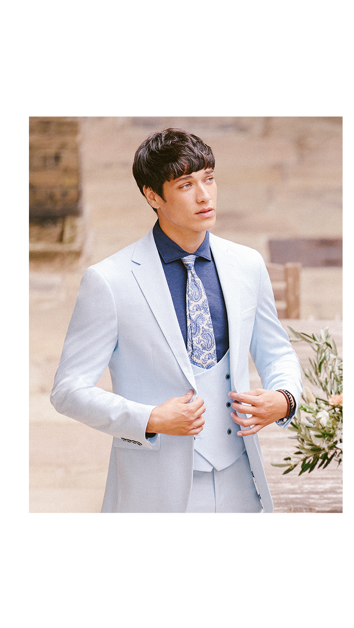 Man at a wedding in light grey three piece summer suit and floral tie