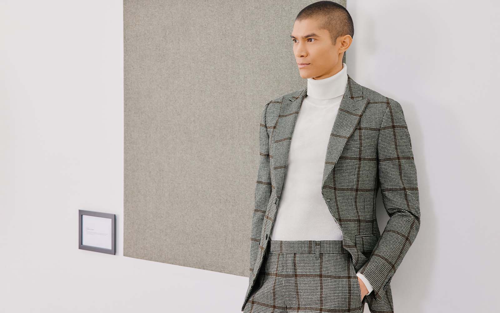 Man in checked grey tweed suit and white roll neck jumper