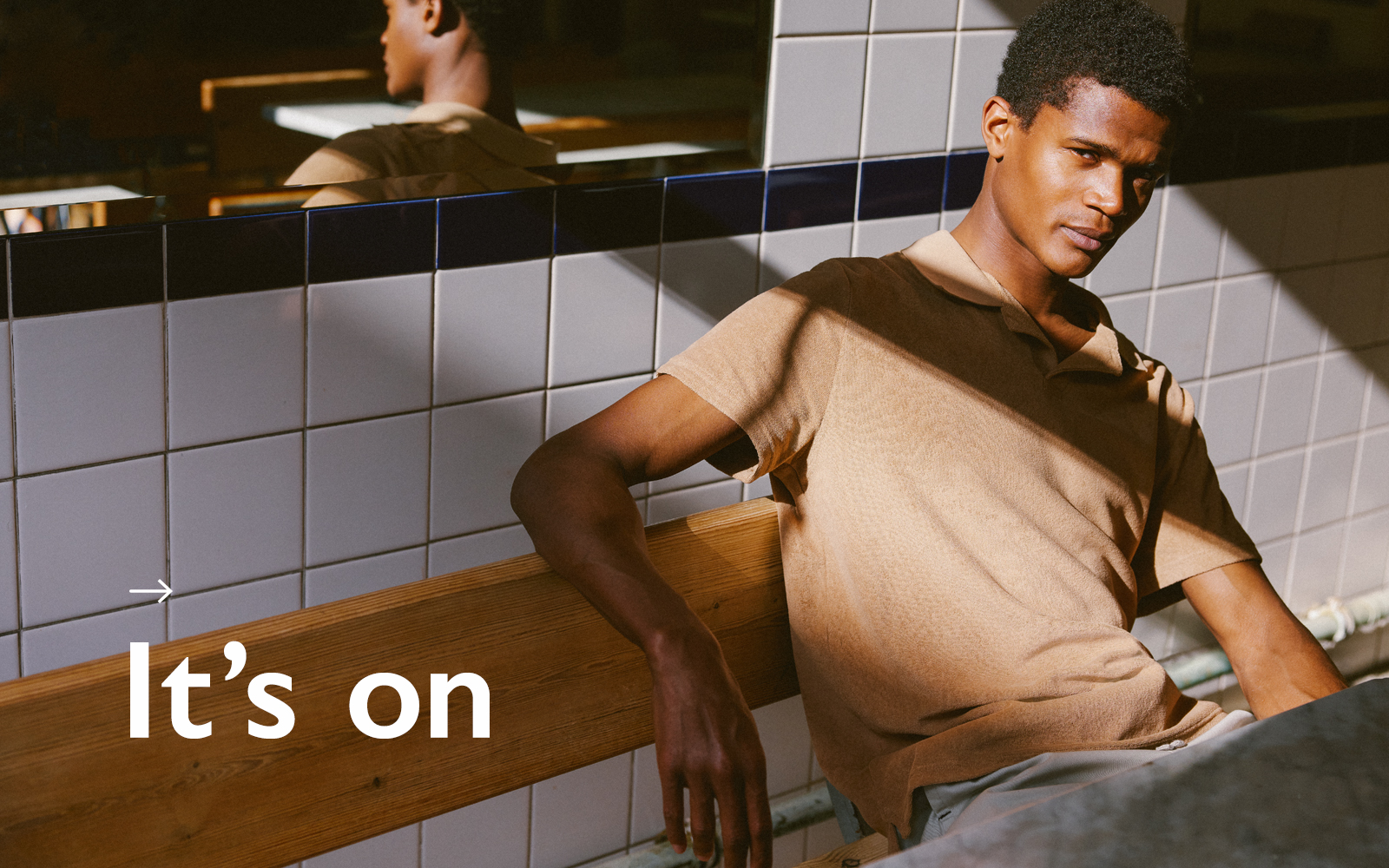 Man dappled in sunlight wearing tan merino polo shirt.