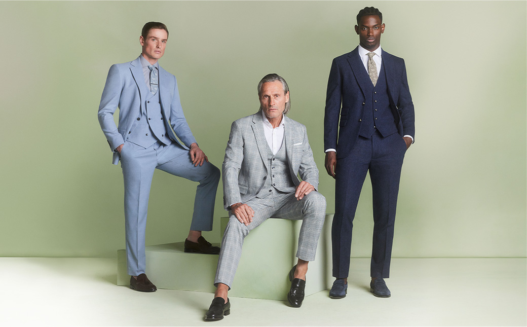 Men laughing at a wedding in grey summer suits and pocket squares and patterned ties 