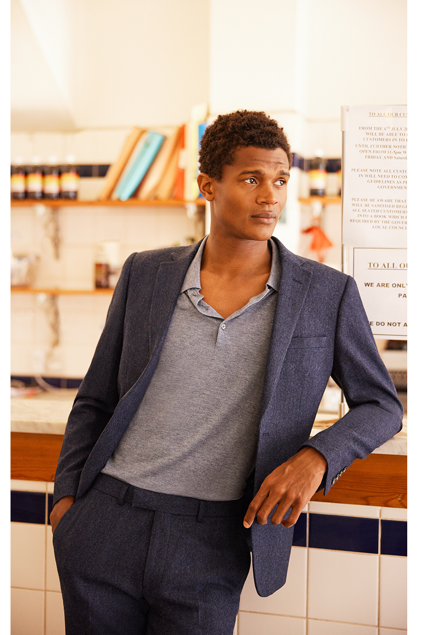 Man at work in stylish grey-blue merino polo shirt and blue suit.