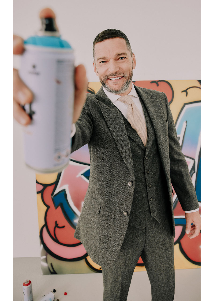 fred sirieix in green three piece suit holding a graffiti can