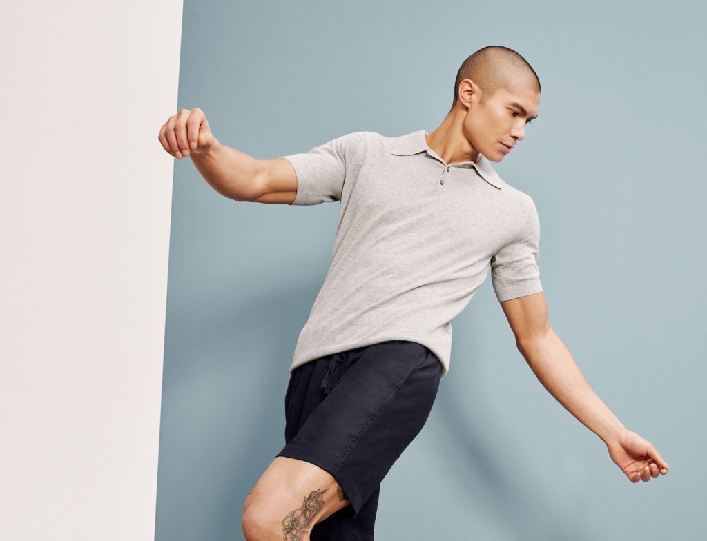 Man dressed for a holiday wearing a grey cotton polo and navy shorts. 