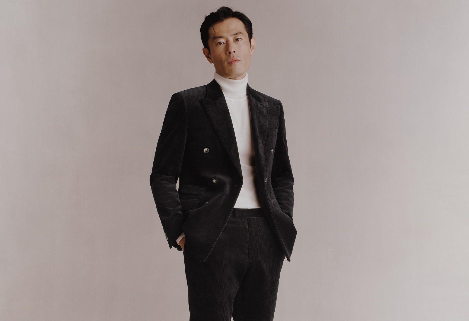 Groom in corduroy statement suit, black with a white rollneck.
